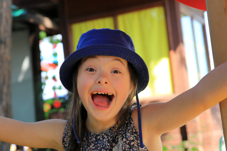girl with additional needs smiling with hat on