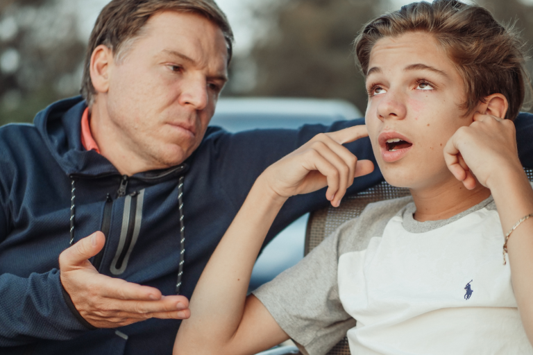 dad talking to son with his fingers in his ear