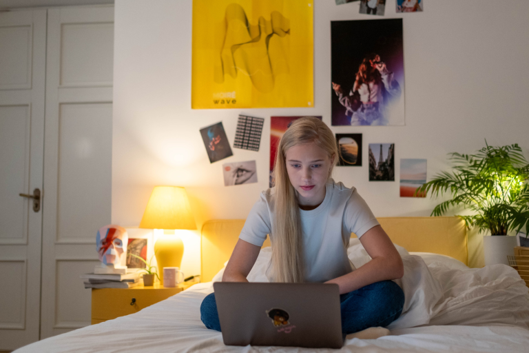 Teenager sitting on a bed on a laptop