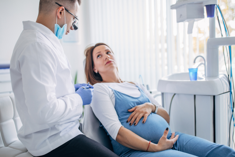 Pregnant lady on dentist chair listening to dentist